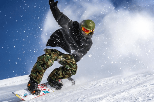 a man riding a snowboard down a snow covered slope